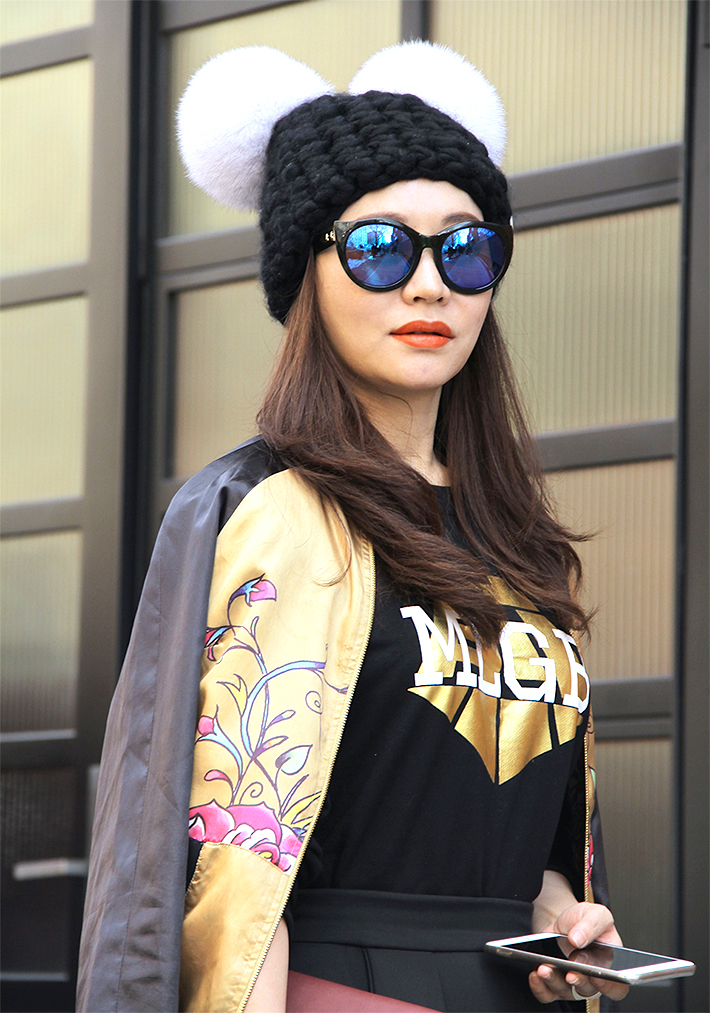 NEW YORK, NY - FEBRUARY 01: Eunice Zhang seen at Industria Superstudios wearing black high waisted pleated skirt, gold Ed Hardy silk embroidered bomber jacket, Jiang sweater, sunglasses and black knitted beanie hat with white pompoms during New York Fashion Week: Men's Fall/Winter 2016 on February 1, 2016 in New York City. (Photo by Georgie Wileman/Getty Images)