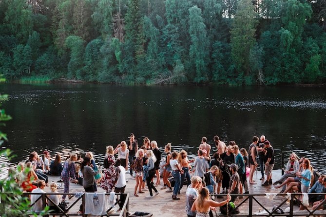 A group of people dancing on a dock near water