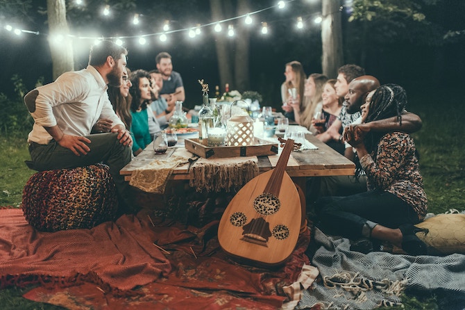 A group of people sitting around an outdoor table next to a guitar