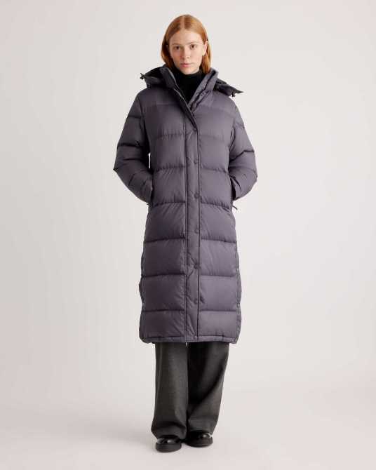A model wearing Quince's Responsible Down Long Puffer Jacket in Carbon Grey