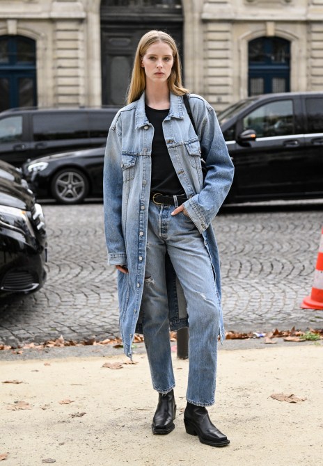 Model Abby Champion is seen wearing a denim coat, black top, light blue jeans and black belt and black boots outside the Chanel show during the Womenswear Spring/Summer 2024 as part of  Paris Fashion Week on October 03, 2023 in Paris, France.