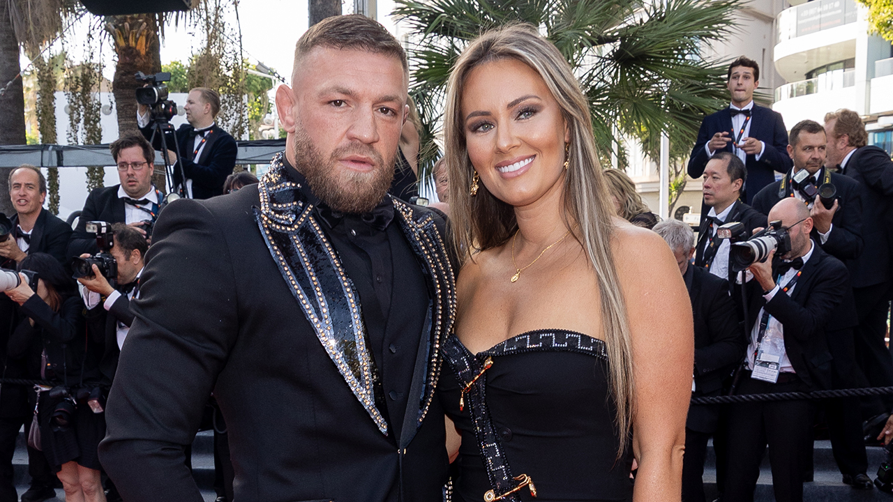Conor McGregor and fiancee Dee Devlin  pose in black suit and dress on red carpet.