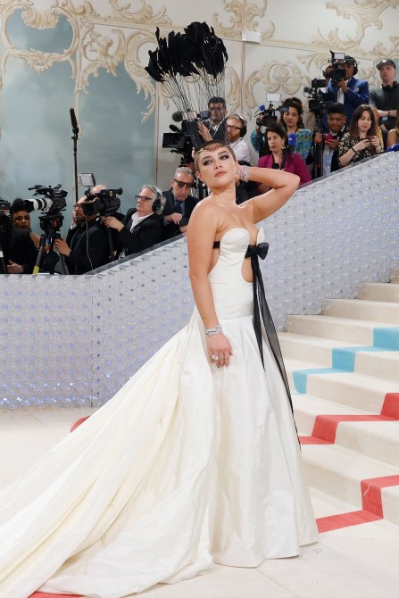 Florence Pugh in a white strapless gown and a black feather hairpiece on the 2023 Met Gala staircase
