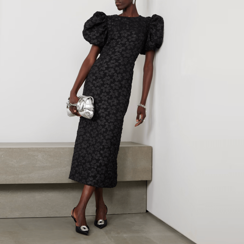 A model wearing a black puff-sleeve midi dress with a floral textured fabric