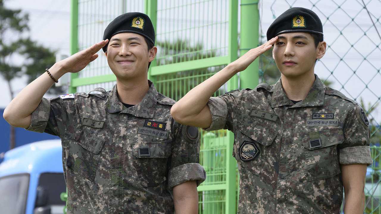 TOPSHOT - K-pop boy band BTS members RM (L) and V salute at an outdoor sporting facility in Chuncheon on June 10, 2025, after their release from 18 months of South Korean military service. Hundreds of fans gathered near two army bases just outside of the capital Seoul where band leader RM -- recently named "Favorite K-pop Artist" at the American Music Awards -- and singer V were discharged.
