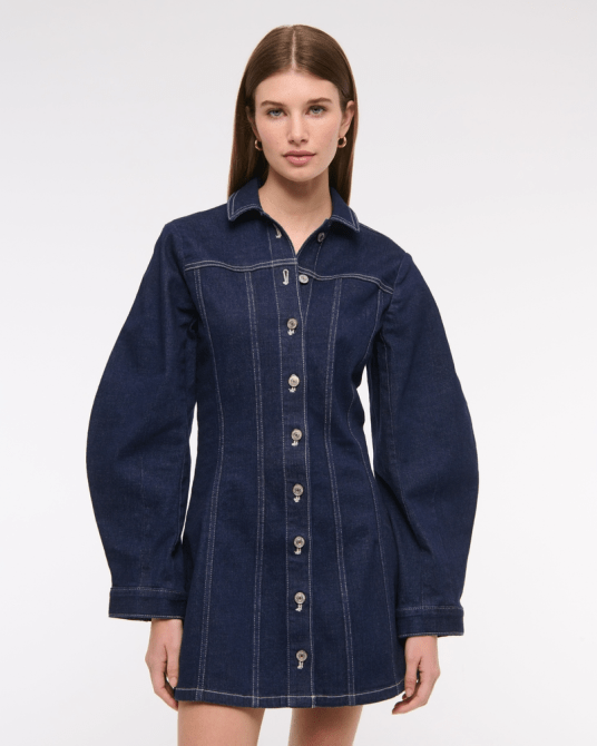 A model wearing the Abercrombie & Fitch Barrel Sleeve Denim Shirt Dress in a dark denim wash
