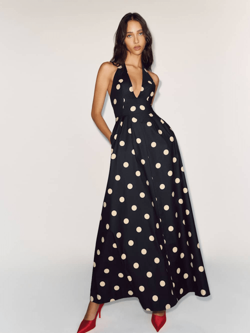 A model wearing Reformation's Diara Dress in a black and cream polka dot pattern